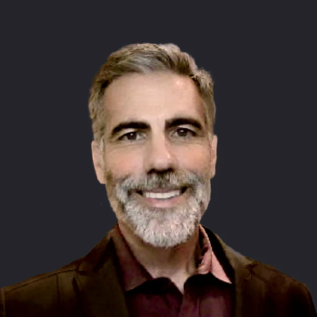 Craig Compiano, DCIM expert, smiles confidently in a dark blazer and burgundy shirt against a simple dark background.